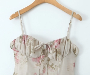 Dettaglio mini abito floreale con tessuto beige, rose rosa e fiocco su un gancio