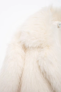 Close-up of fluffy faux fur texture on lapel and shoulder of a cream-colored coat