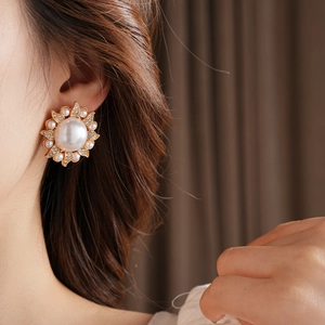 Détail de boucles d'oreilles vintage tournesol avec perles et cristaux sur métal doré
