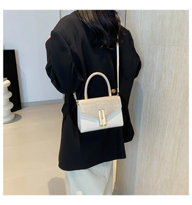 Model view of cream shoulder bag with gold glitter flap and metal bar details