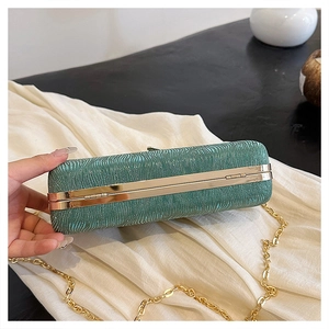 Detail of emerald green pleated evening clutch with gold metal frame and cross-body chain