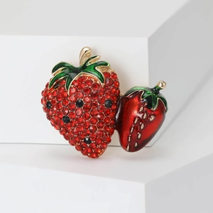 Elegant strawberry brooch with red rhinestones and gold base on a white display stand