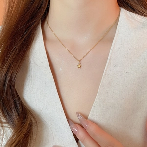 Dettaglio della collana con pendente a stella dorata e zircone sul collo di una modella