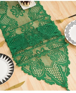 Close-up of green lace table runner with hollow floral embroidery and tassels