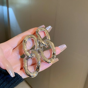 Détail de boucles d'oreilles irrégulières en métal argenté avec texture martelée unique