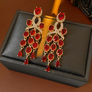 Detail van vintage gouden oorbellen met ovale rode edelstenen en elegante kwastjes