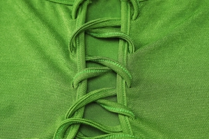 Vue détaillée de la texture du tricot vert et du design des lacets croisés sur la robe