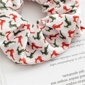 Macro detail of knit Christmas scrunchie featuring red and green reindeer patterns