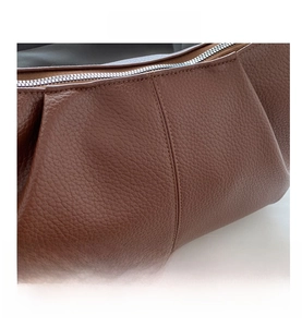 Primo piano della texture in pelle litchi marrone e dettagli della zip argentata
