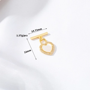 Macro detail of a gold heart charm with mother of pearl and zircons for DIY jewelry