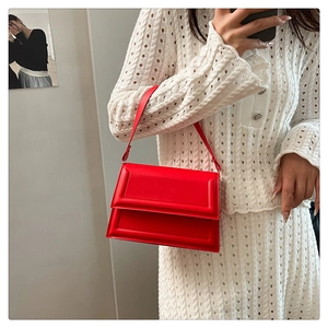 Detail of red PU leather handbag with smooth texture and stylish embossed lines