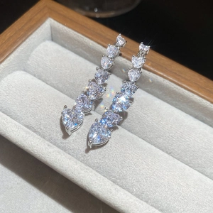 Close-up of 18K gold plated heart earrings with zircon stones on a grey velvet box