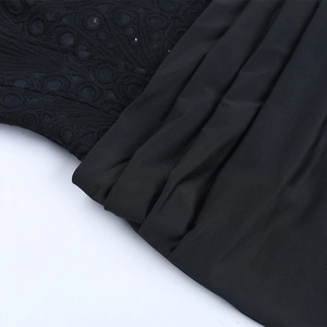 Detailweergave van zwarte kantstiksels en geplooide stoftexturen op de jurk