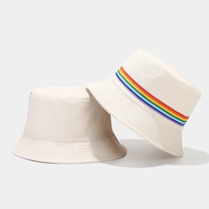 Close-up of beige canvas bucket hats with vibrant rainbow stripe webbing detail