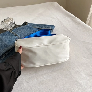 White canvas shoulder bag with blue nylon strap, minimalist sporty style shown with denim
