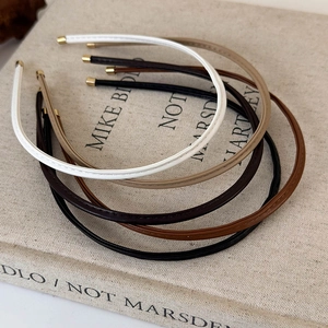 Detail of four faux leather headbands in white, khaki, coffee, and black with metal tips