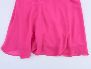 Dettaglio dell'abito in chiffon rosa con trama morbida e orlo a pieghe fluente
