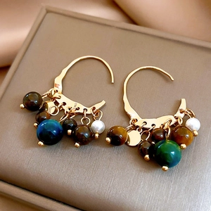 Detail of vintage gold earrings with multi-colored tiger eye beads and pearls on silk
