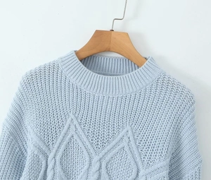 Detail of light blue cable knit sweater with crew neck and dropped shoulder seams