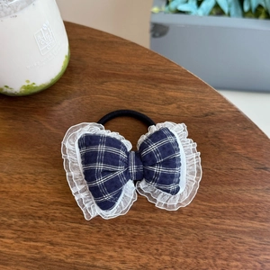Blue and white plaid bow hair scrunchie with lace edges on a wooden background