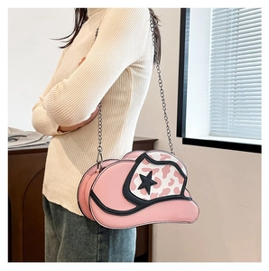 Pink cowboy hat shaped crossbody bag with star pattern and chain strap on model