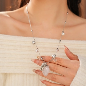 Detail of strawberry pendant necklace with silver chain and pearls on model neck
