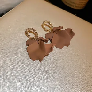Vintage gold and dark brown petal drop earrings on a textured off-white background