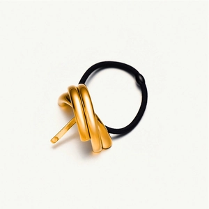 Elegant gold metal knot hair tie with black elastic band on white background