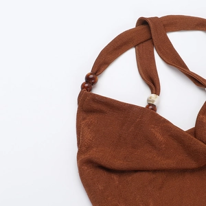Detail of brown halter neck dress showing resin beads and textured knit fabric texture