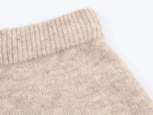 Macro detail of oatmeal ribbed knit fabric texture and high-quality stitching on a skirt