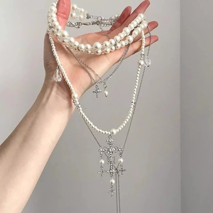 Macro shot of layered baroque pearl cross necklace with rhinestones and silver chains