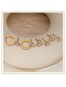 Detail of gold clover stud earrings set with sparkling zircons on a ceramic display