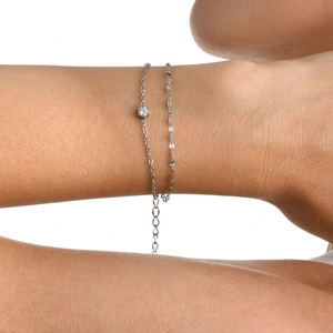 Detail of double-layer stainless steel cross bracelet with a bright round zirconia gemstone