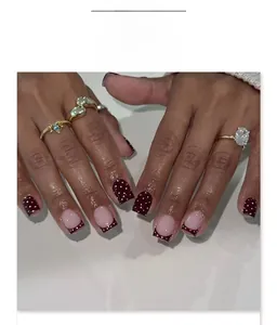 Dettaglio macro di unghie bordeaux con pois bianchi e design French tip moderno