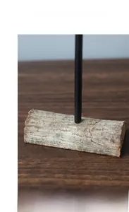Detail of a natural wood base with a matte black metal rod for Nordic style decor