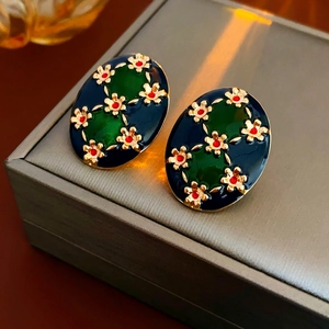 Dettaglio di orecchini vintage ovali con smalto blu, inserti verdi e motivi floreali