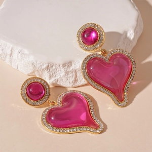 Detail of pink resin heart earrings with gold trim and sparkling rhinestone edges