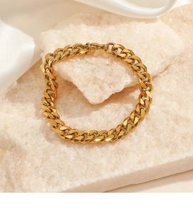 Detailed close-up of golden Cuban link bracelet on a white stone with lobster clasp