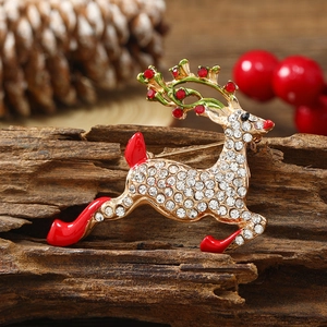 Exquisite gold reindeer brooch with sparkling crystals and red enamel on wood background