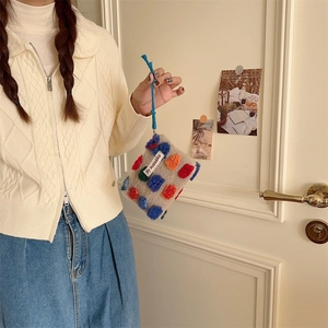 Detail of beige knit bucket bag with colorful pompoms and drawstring handle by sozakka