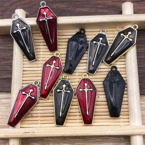 Close-up of gothic coffin cross pendants in red and black enamel for DIY jewelry