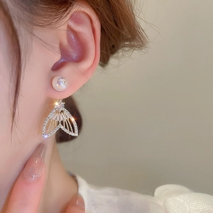 Élégantes boucles d'oreilles queue de sirène dorées avec perles et zircons sur modèle