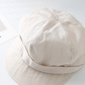 Close-up of soft pleated cotton fabric and short brim on a beige sun hat