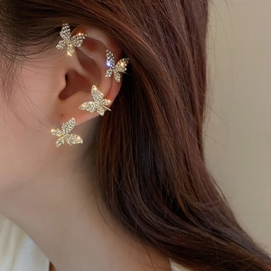 Elegant gold butterfly ear clips with white rhinestones on a model's ear