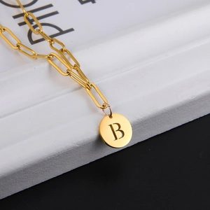 Detailed view of golden paperclip chain necklace with a letter B round pendant charm