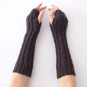 Detail of dark brown cable knit fingerless gloves showing thick texture and thumb hole