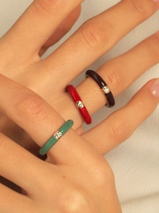 Three colorful enamel rings with central zircon stones worn on fingers for a trendy look