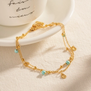 French vintage double layer gold anklet with turquoise beads and small shells on white ceramic