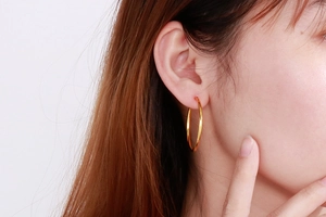 Model wearing minimalist gold stainless steel hoop earrings in a side-view shot