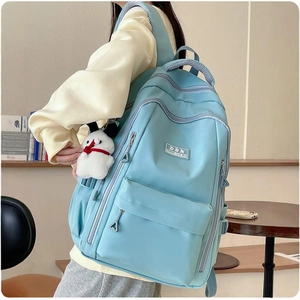 Water-resistant light blue student backpack shown from a side view on a model